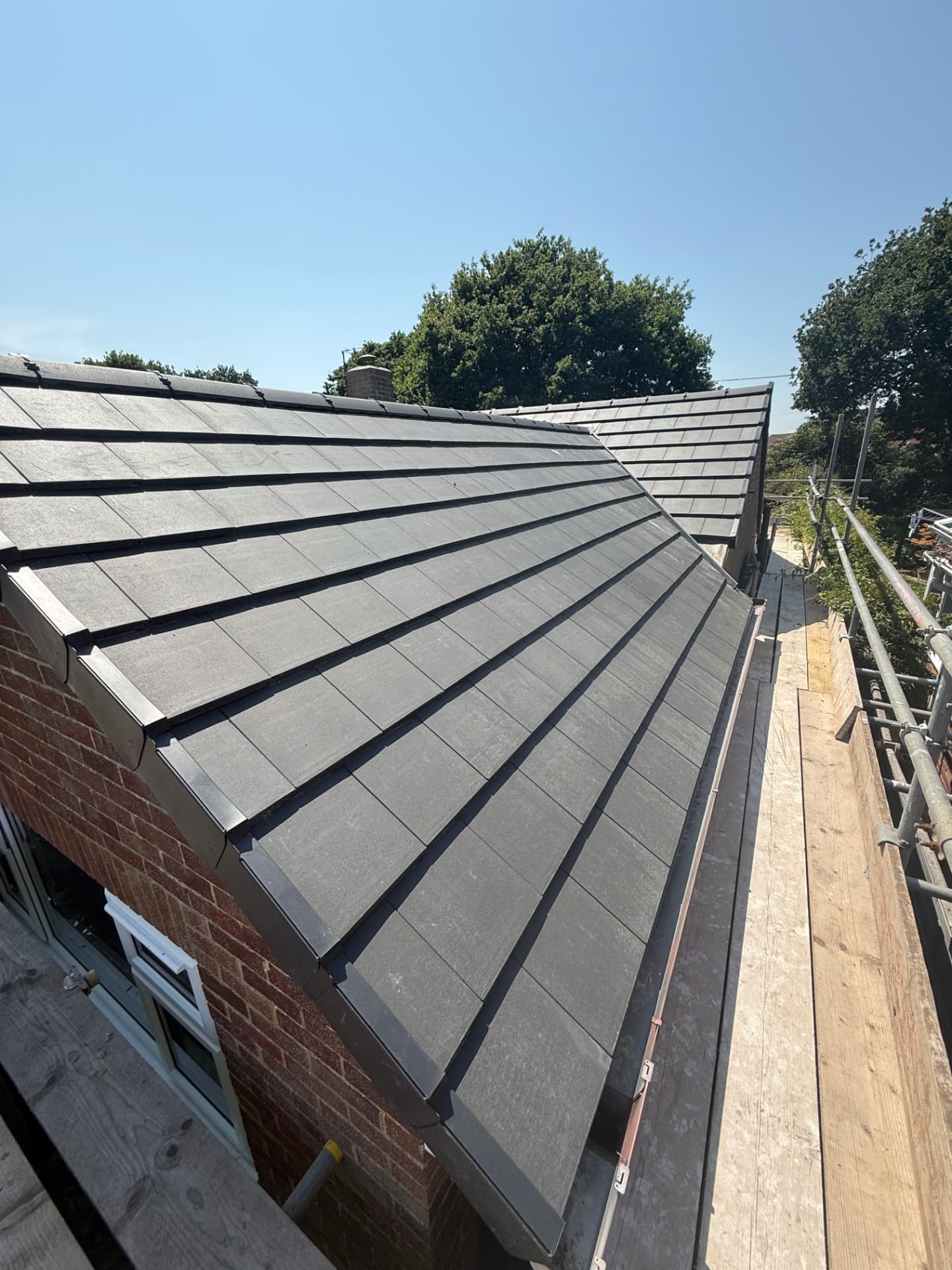New grey flat-profile tiled pitched roof with dry verge