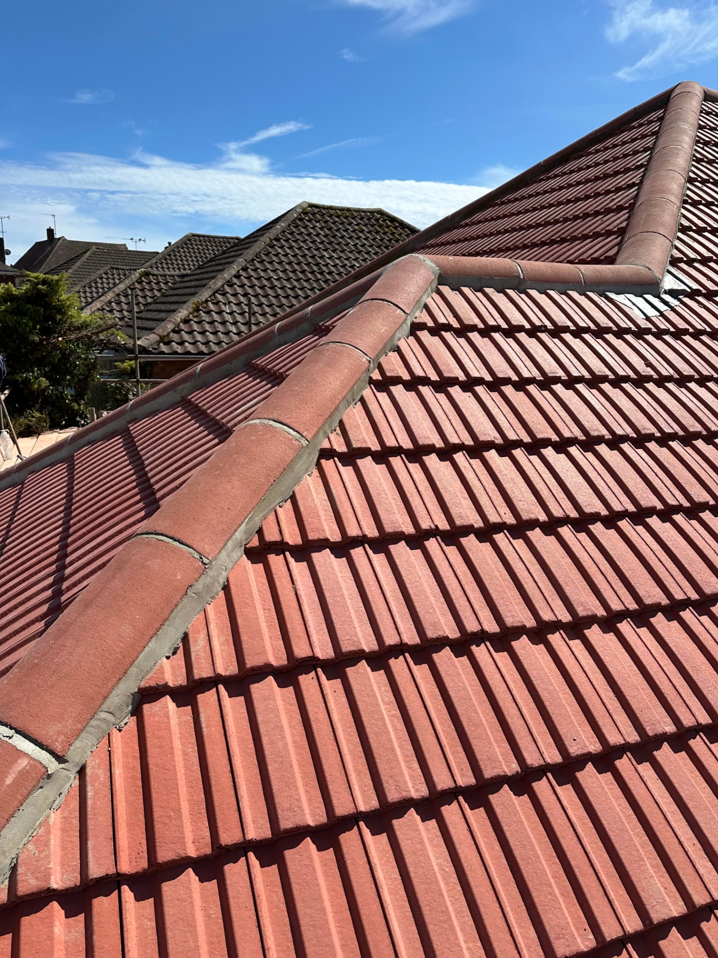 Red clay-effect tiled pitched roof with bedded ridge and hip tiles